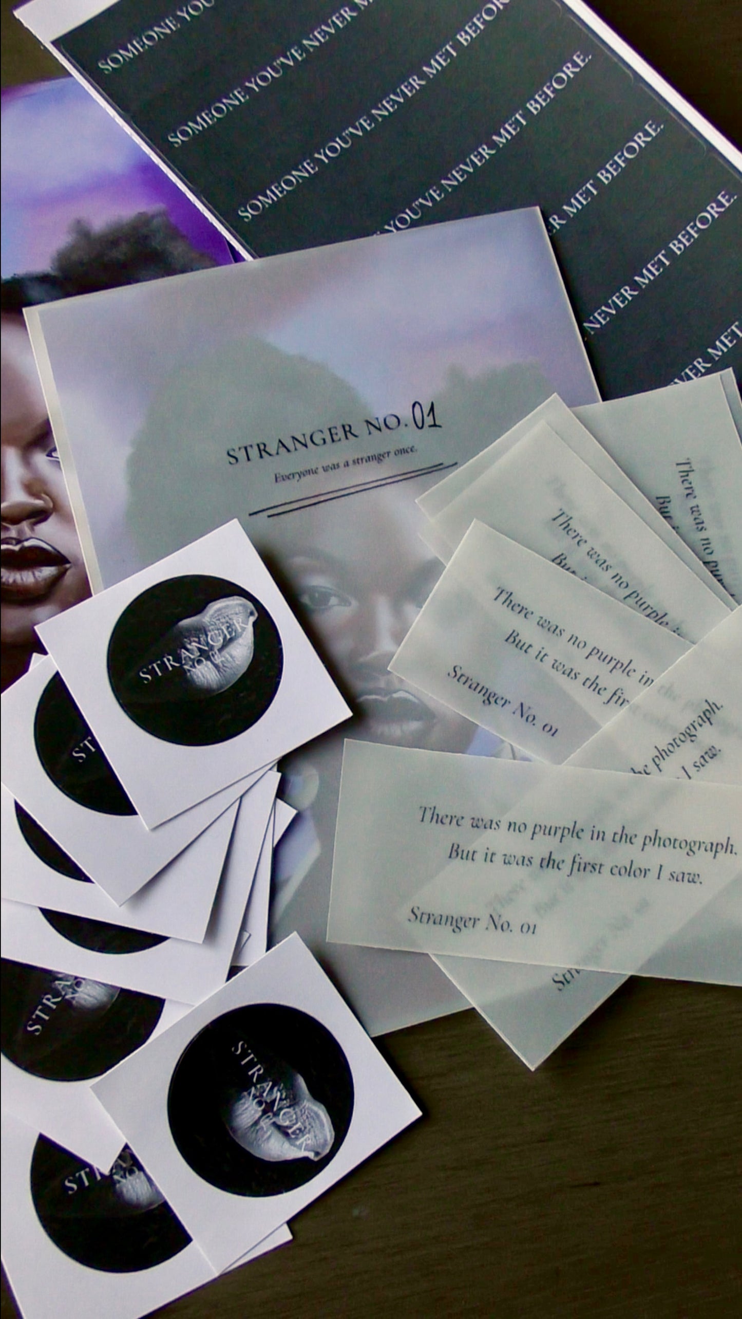 Collection of 'Stranger No. 01' promotional materials including stickers and cards on a dark surface.