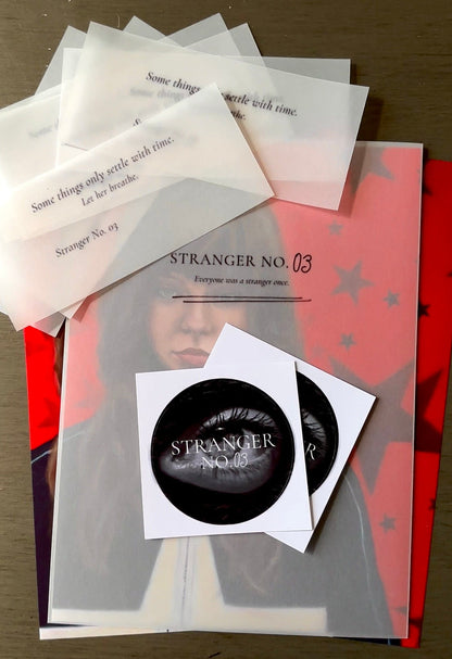Collection of 'Stranger No.03' themed items including ephemera cards and stickers on a wooden surface.