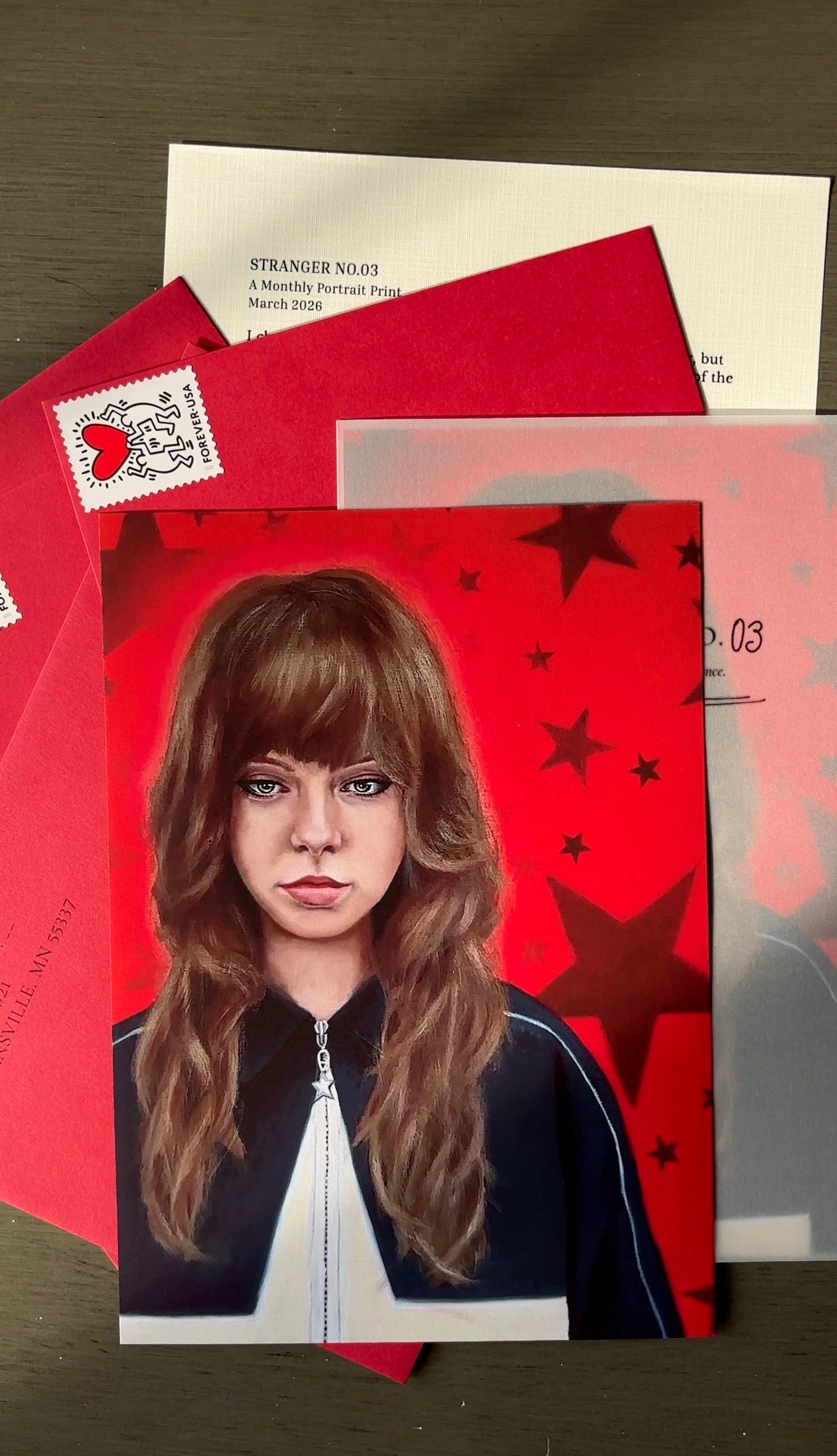 Card with a portrait of a person on a red background with stars, surrounded by other cards and an envelope.